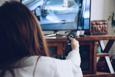 Young girl holding a remote to flip channels on a TV